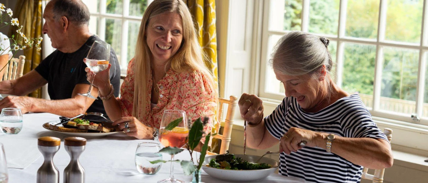 Two women and a man sitting down to a meal in a bright restaurant 