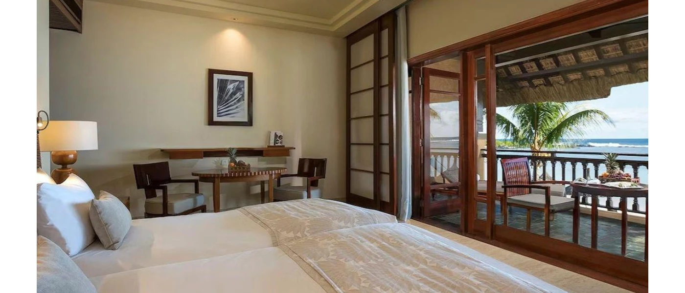 Bohemian-style neutral bedroom with wooden patio doors overlooking a furnished balcony
