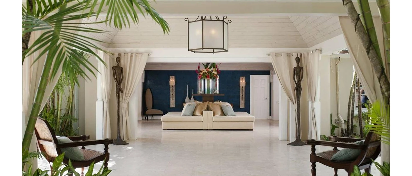 Bright and welcoming reception area with white walls and tiled floor, tropical plants and dark-wood chairs