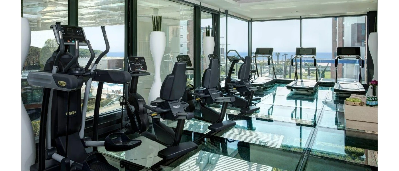 Modern gym with wraparound windows and black treadmills, bikes and cycling machines, plus a glossy floor