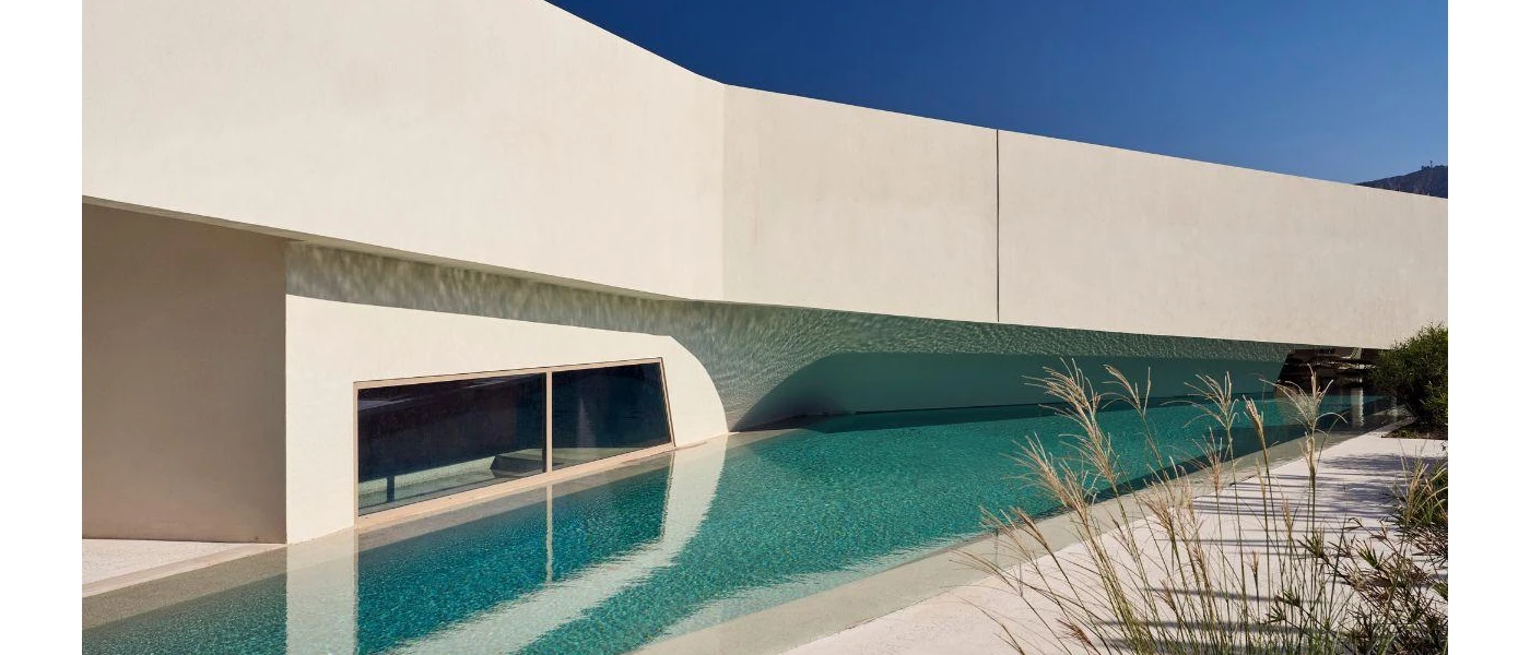 Futuristic looking angular building with a window and wedge-shaped swimming pool next to it