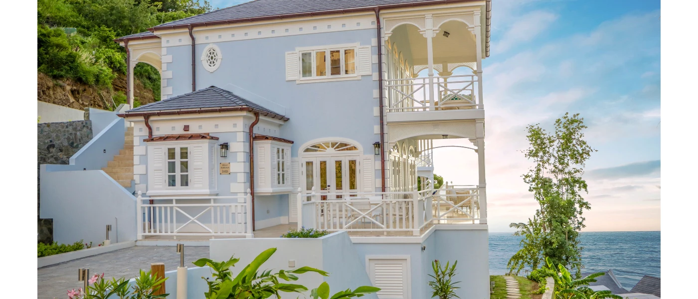 Powder blue painted building with white balconies and a view of the ocean