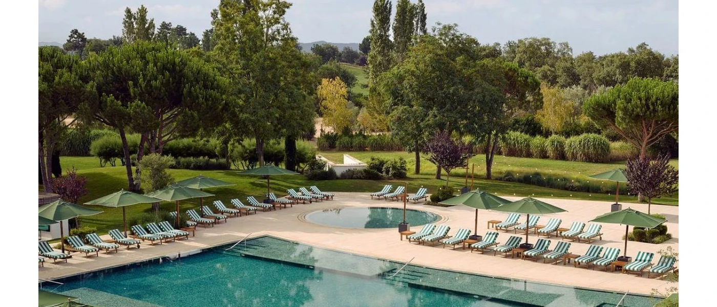 Rectangular pool and circular swimming pool surrounded by green parasols, green and white striped cushions and lawned gardens