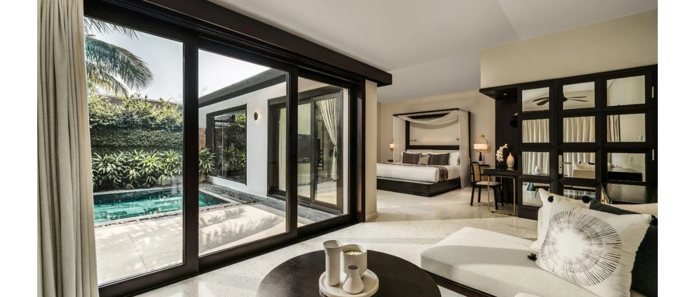 Stylish villa with a black and white colour scheme, a bed and living area and full-length patio doors the overlook a courtyard with a square pool