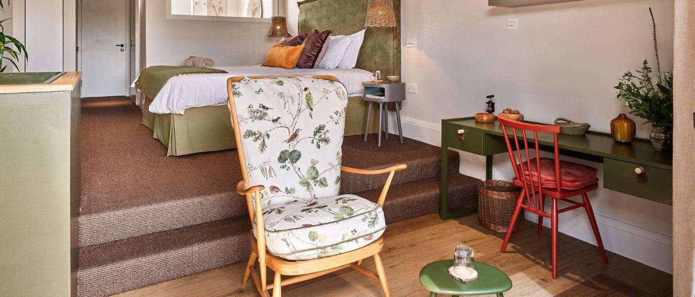 Patterned chair in a seating area of a hotel room, next to a wooden desk with a red chair