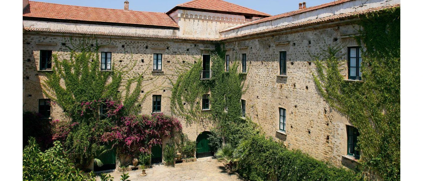 Stone-walled palazzo with climbing greenery and terracotta-tiled rooftops