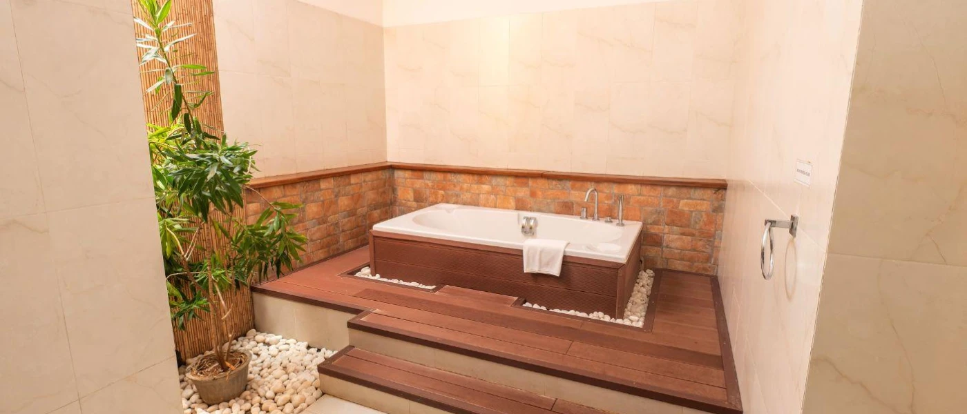 Outdoor wooden bath on a raised platform, surrounded by stone walls and plants