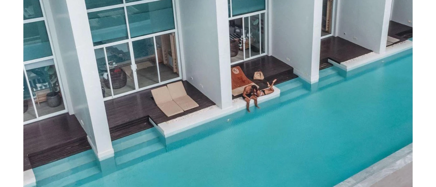 Man and woman relax on a private wooden deck next to a shared pool