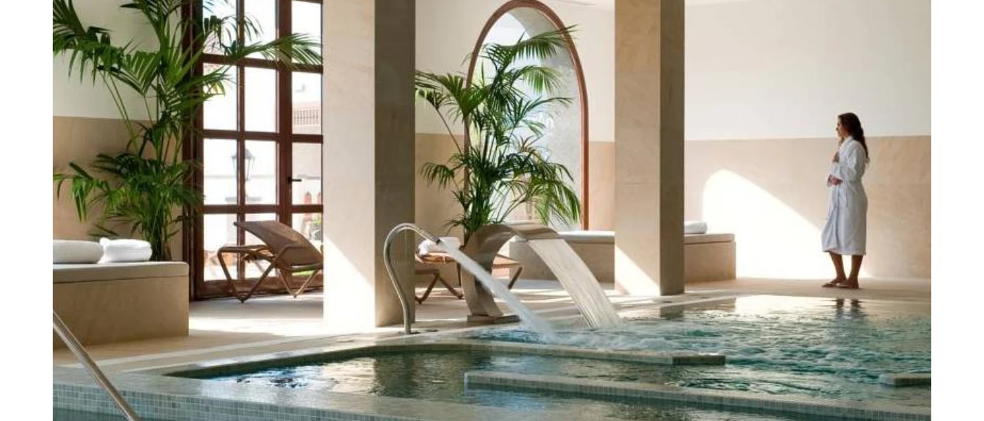 Woman in a white robe relaxing by the indoor pool at Hacienda del Conde spa, Tenerife