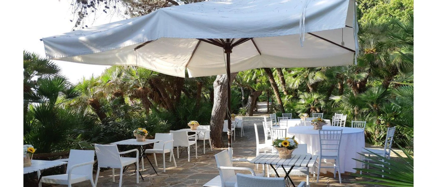 Terrace surrounded by gardens, with white tables and chairs and large parasols