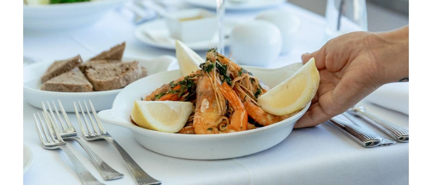 White tablecloth with plates of prawns, lemon slices and bread