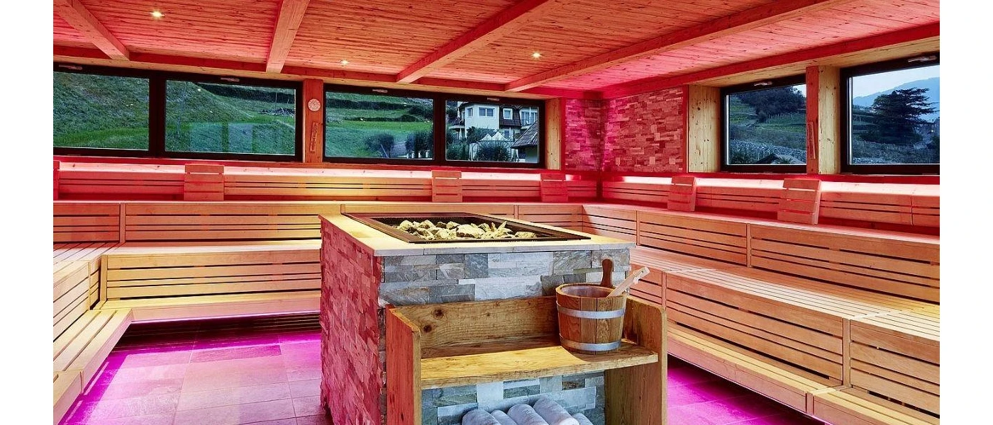 Wooden sauna  with pink LED lighting and windows with views of the greenery and mountains beyond