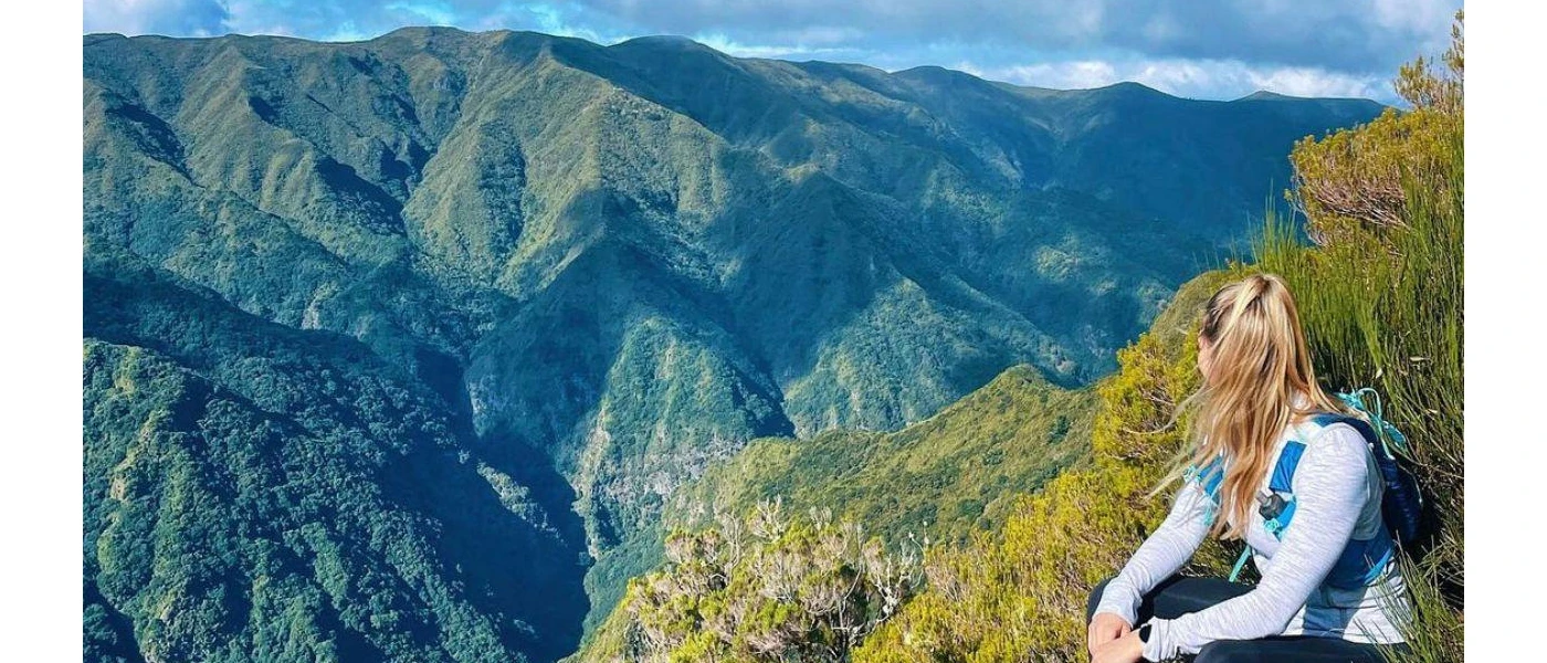 Woman in active wear with long blonde hair sitting and enjoying the view over the mountains