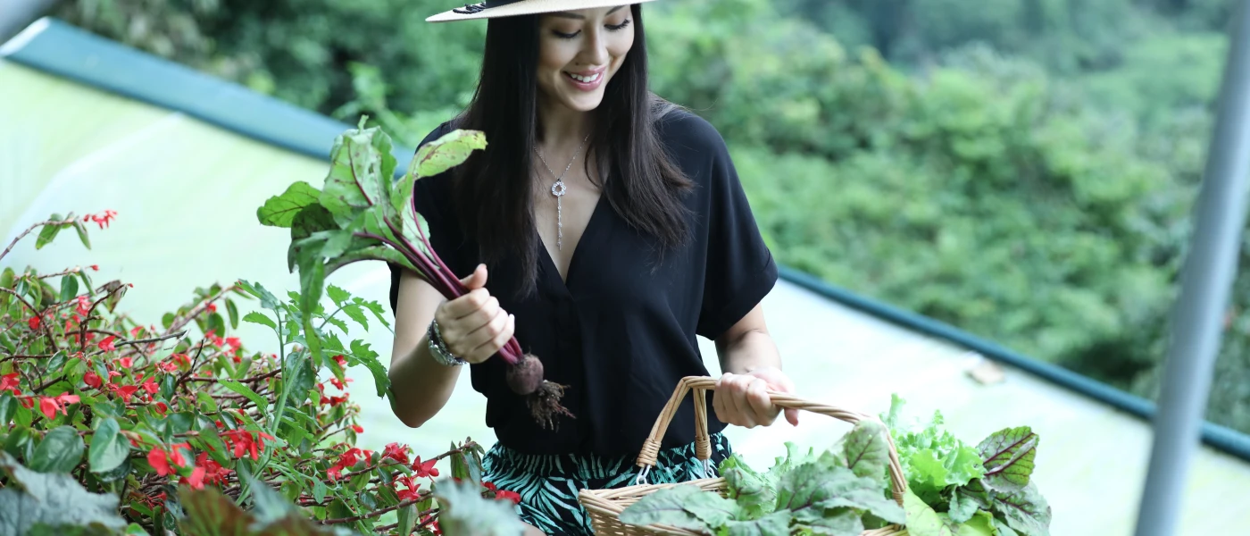 Smiling woman in a straw hat and black shirt holding organic vegetables