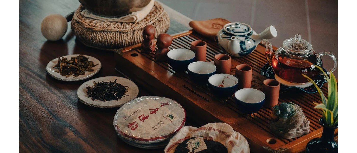 Wooden tray with a glass pot of tea, and various ingredients in bowls next to it