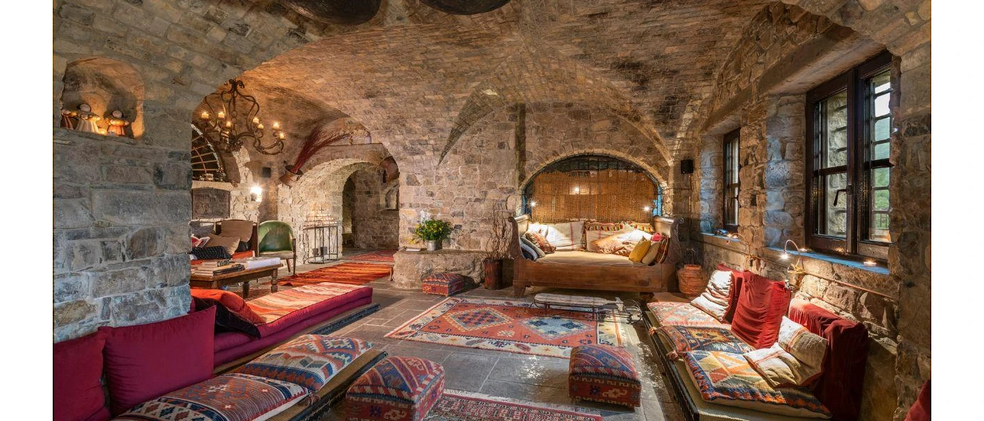 Cosy room with stone walls and ceiling, low-level patterned chairs and candlelight
