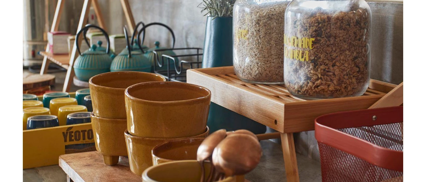 Two full jars of granola laid out next to ceramic bowls on a breakfast bar