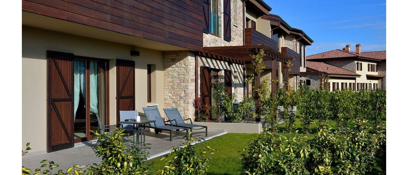 Terrace with black loungers overlooking a lawn, in a hotel room
