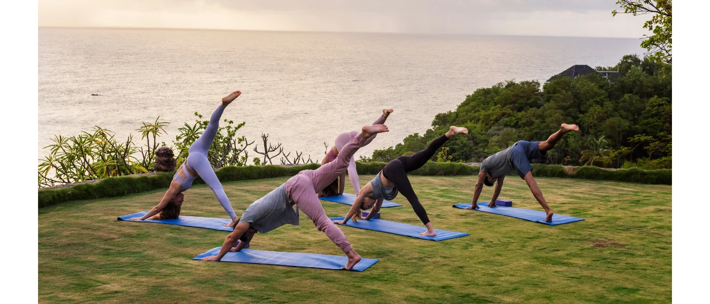 Group yoga fitness class taking place on a lawn overlooking the sea
