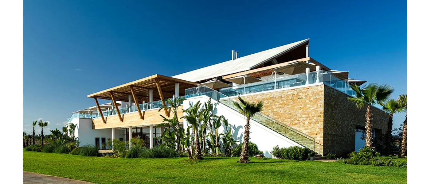 Angular, contemporary building with glass balconies surrounded by a grassy lawn and palm trees
