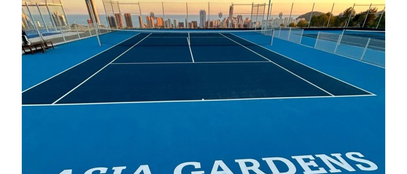 Blue tennis courts with a view of the Alicante skyline at sunset
