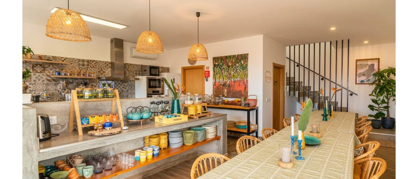 Dining area with long communal table, bohemian lighting and a bar laid up with bowls and cups