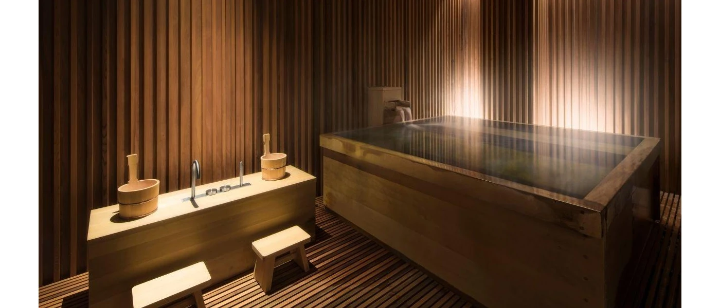 Spa room with wooden walls and flooring, a circular bath and a table with wooden buckets and stalls