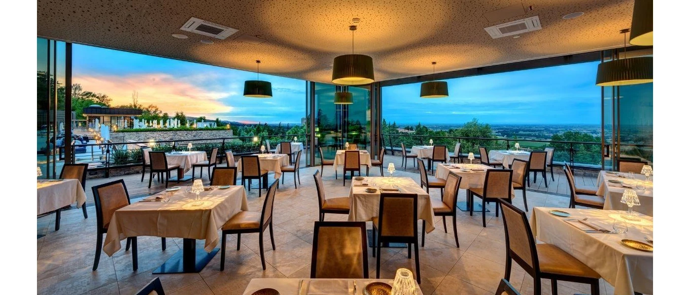 Softly lit restaurant with neutral coloured table cloths and floor-to-ceiling windows with a countryside view