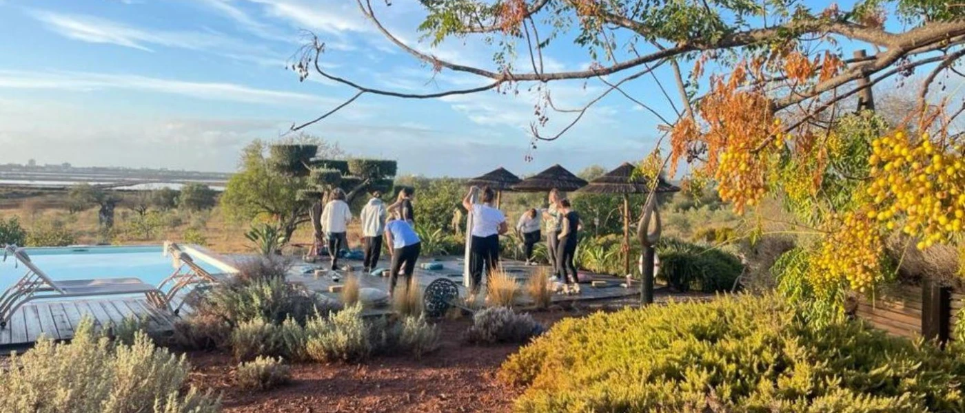 Group stand in a circle outside among gardens under a blue sky