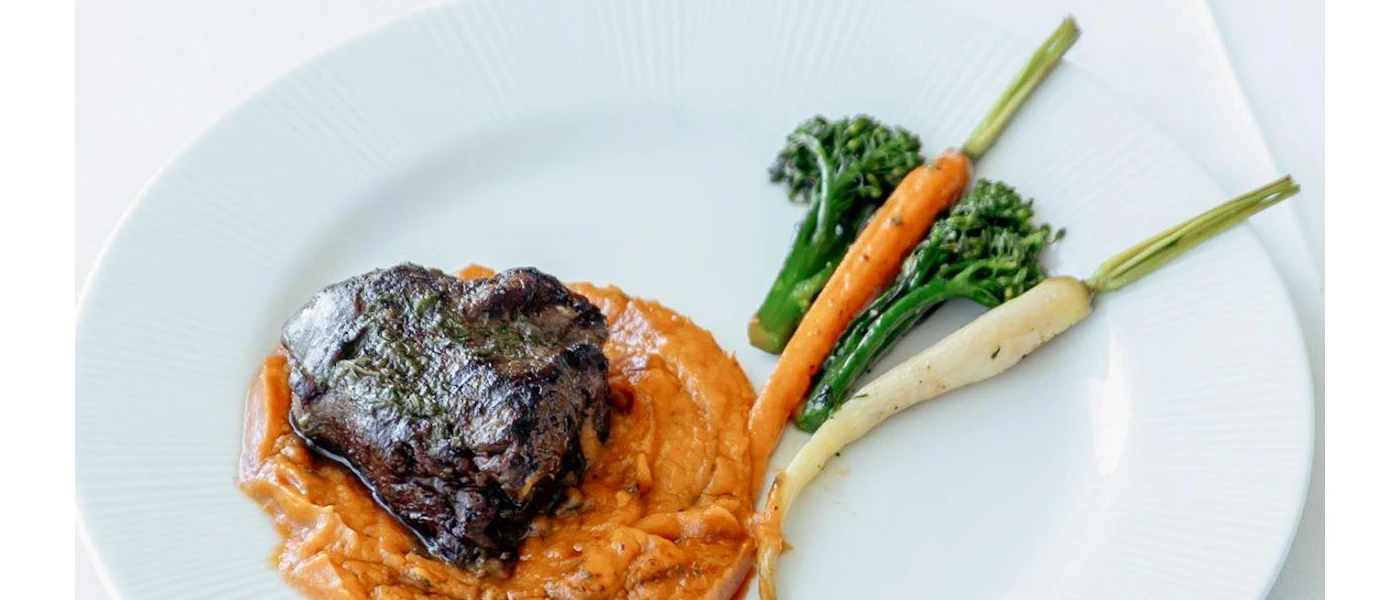 Grilled meat in a pumpkin-coloured sauce with broccoli and carrots