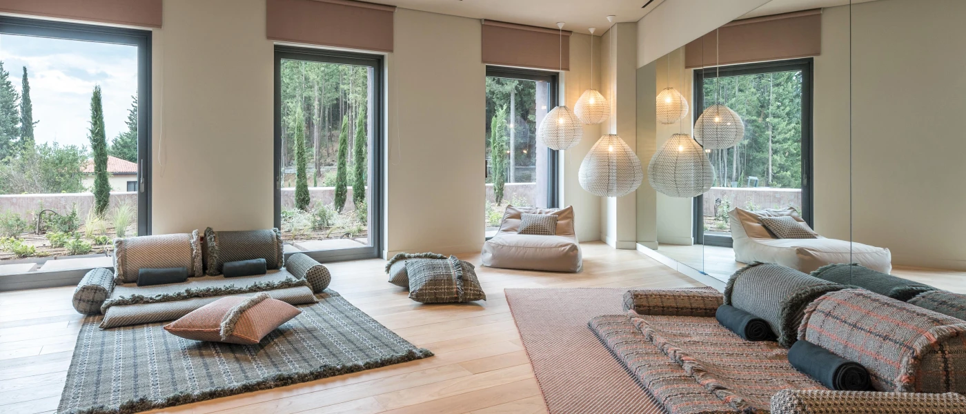 Relaxation room with patterned floor blankets and cushions, hanging pendant lights and floor-to-ceiling windows