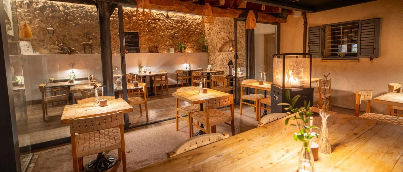 Indoor restaurant with wooden tables and chairs nicely lit for an evening meal 