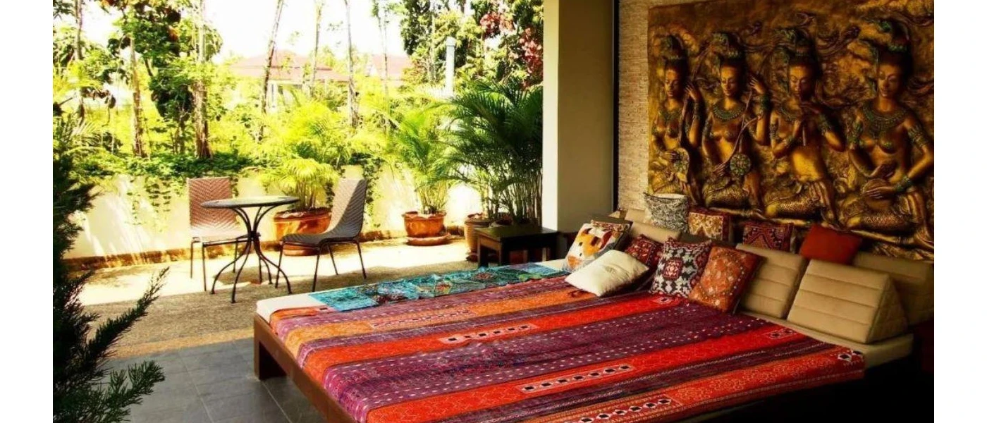 Daybed with colourful blanket and cushions, in front of a wall mural depicting Hindu images