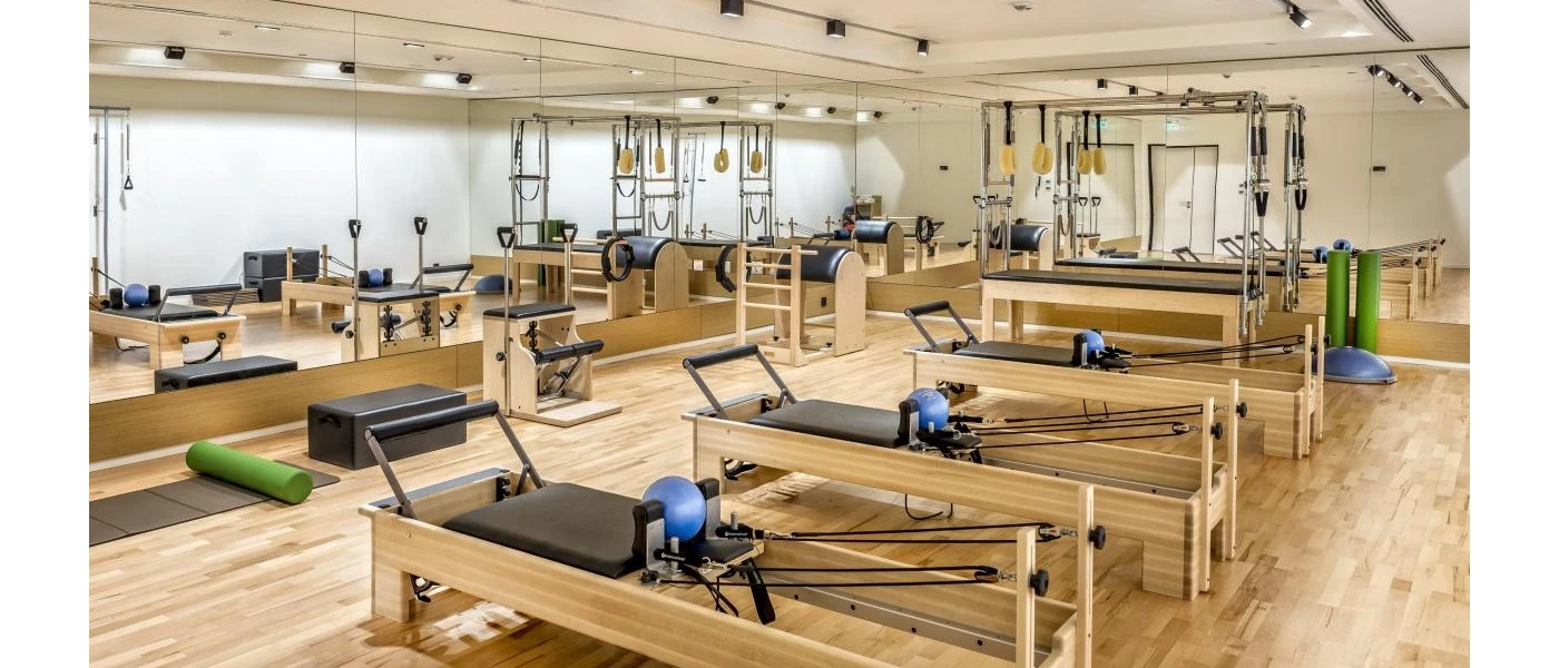 Reformer Pilates machines in a studio with wooden floors and full-size mirrors