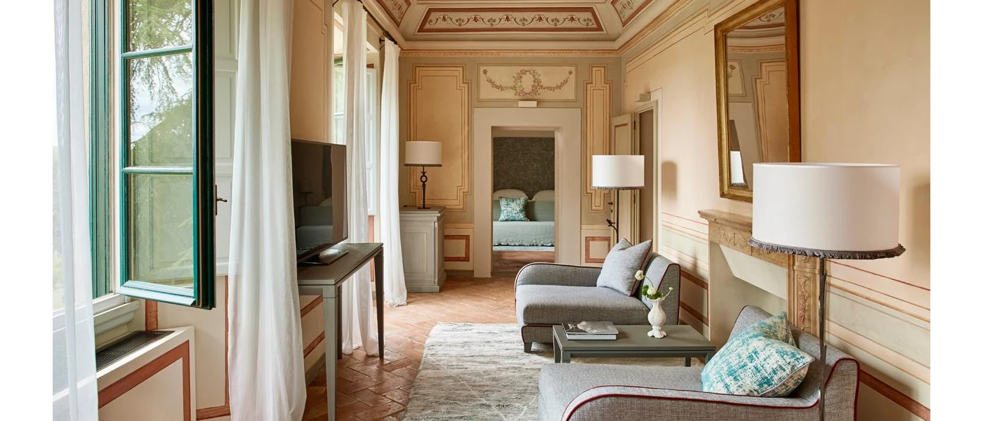 Grand hallway with intricate frescoes, grey armchairs and blue cushions