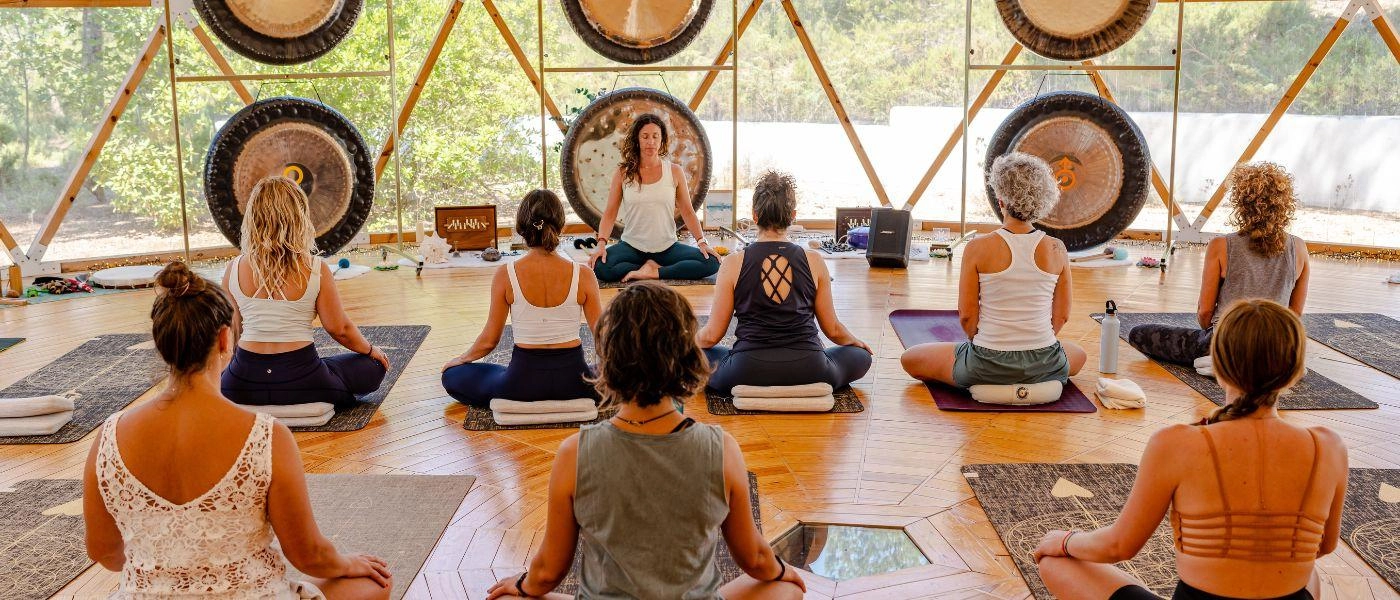 Group in active wear sit on purple mats and meditating