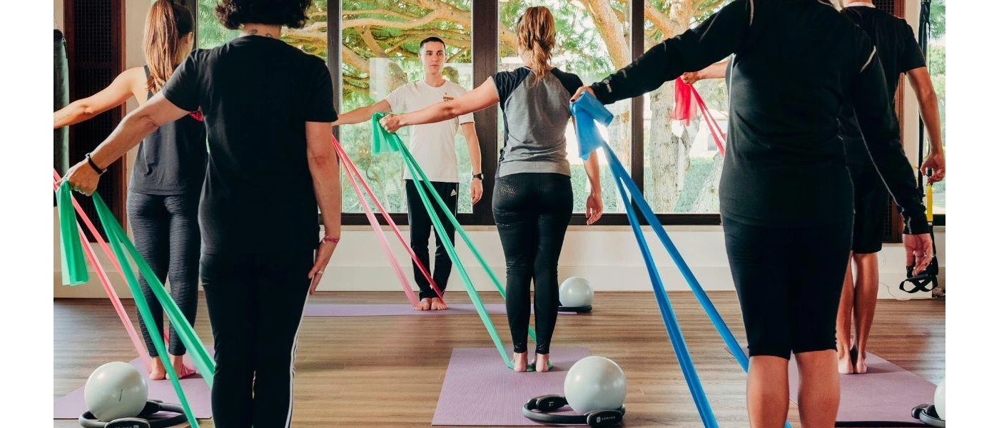 Group in active wear take part in a class using yoga mats, colourful stretchy bands and medicine balls