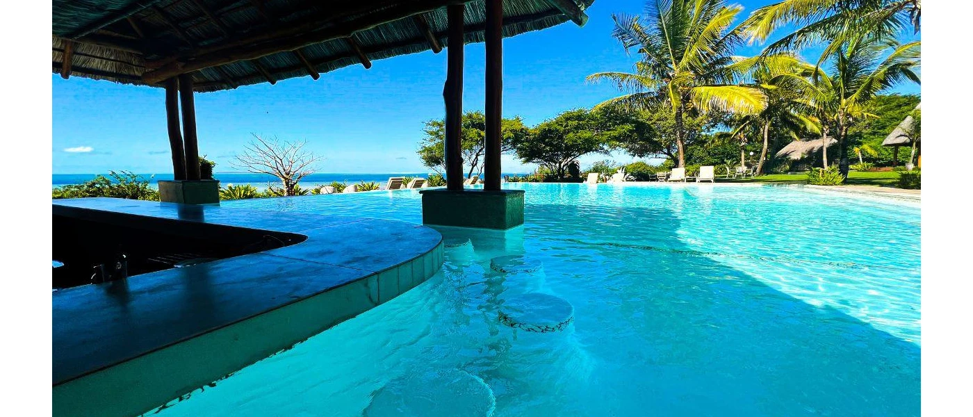 Swim-up bar in an infinity pool surrounded by loungers and greenery