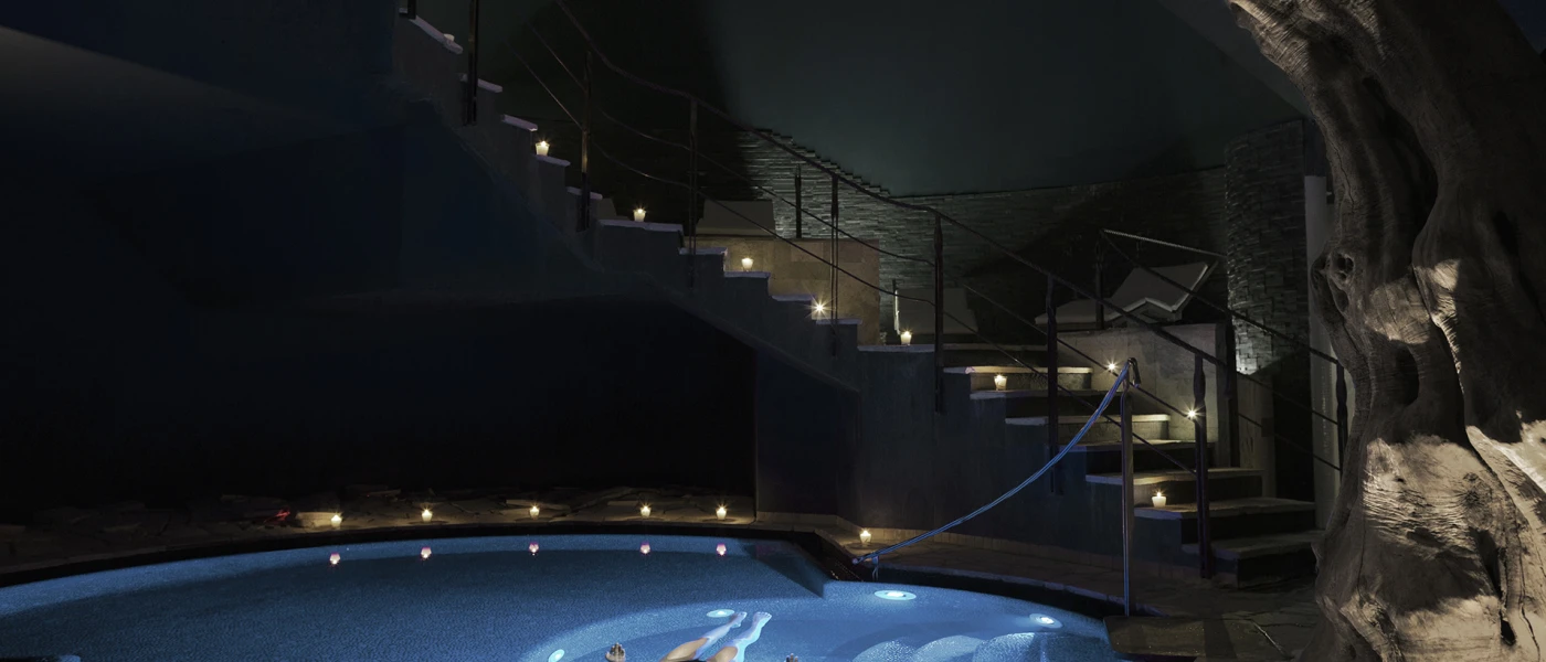 Woman floating on her back in a pool lit by candles