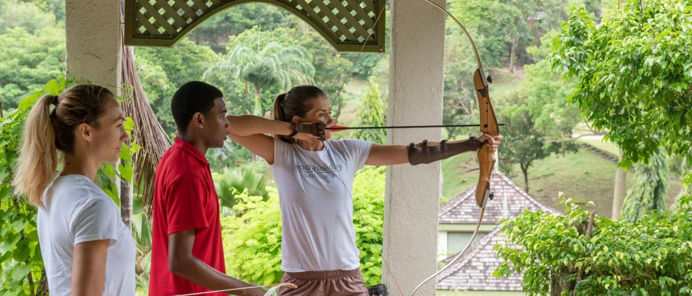 Two guests taking part in an archery activity as an instructor watches on