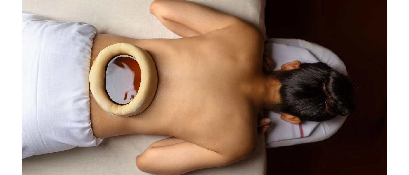 Woman on her front having a warm oil on her lower back