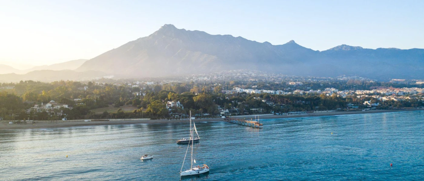 Spanish coastline with mountains in the background and boats bobbing in the sea