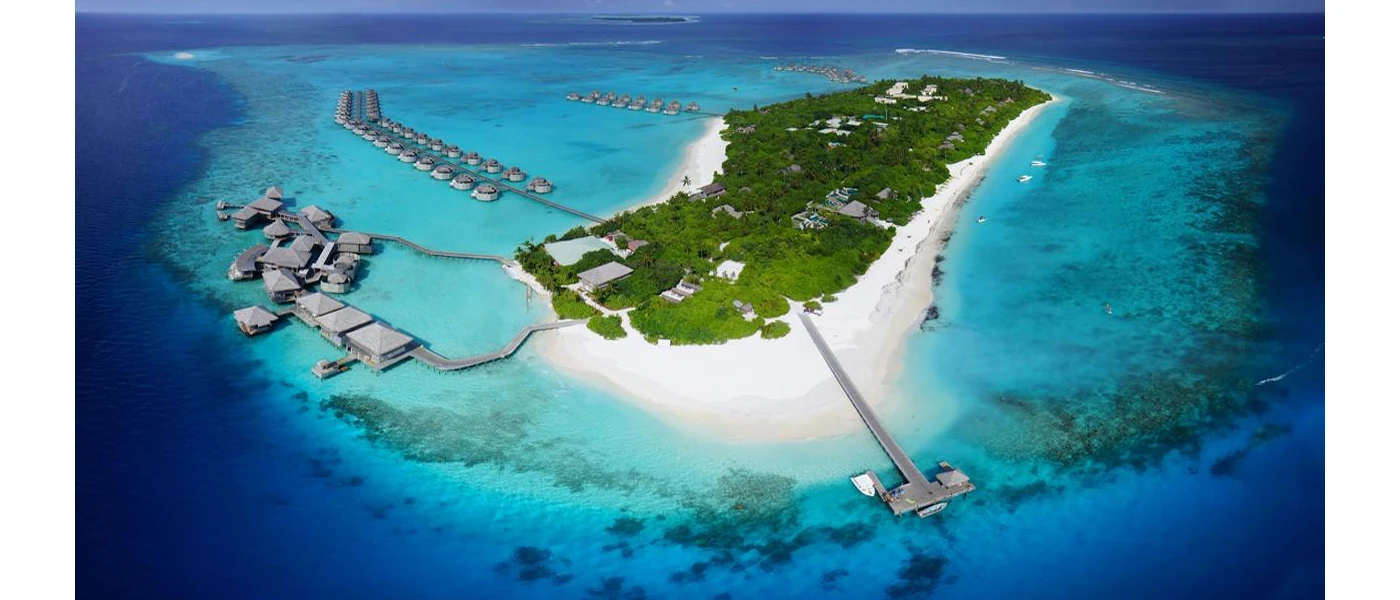 Tropical island in the Maldives, with a tropical interior, bright white sands, turquoise shallows and lines of overwater villas