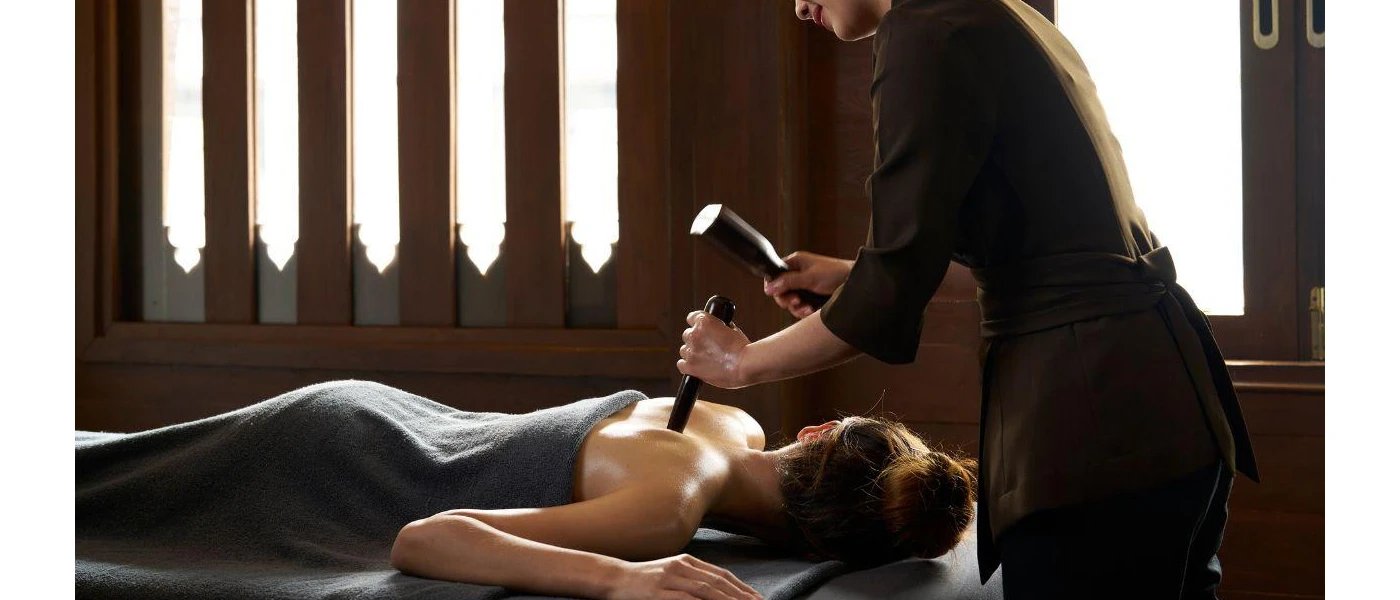 Woman lies on her back in a blue towel as a therapist massages her 