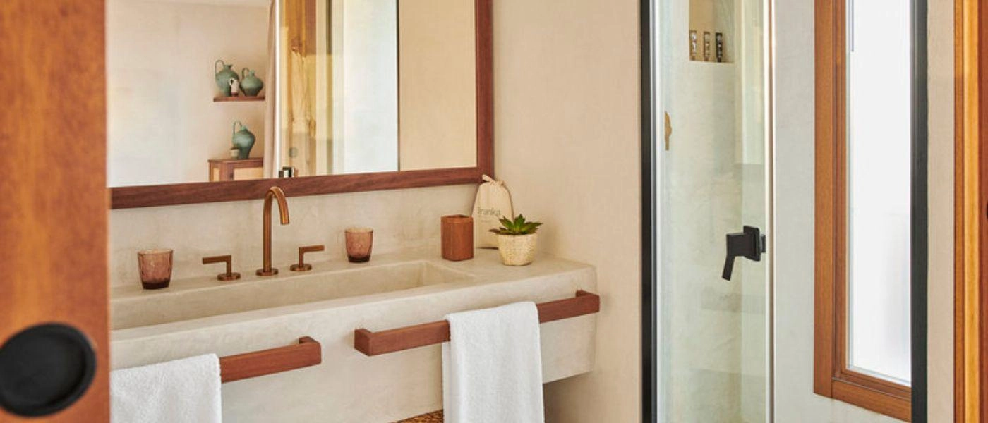 Boho-style modern bathroom with wood-framed mirrors, a white vanity unit and small potted plant