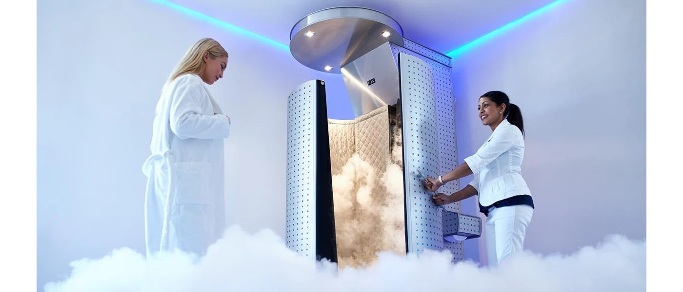 Two women in clinical white clothes standing outside a chamber in a spa setting