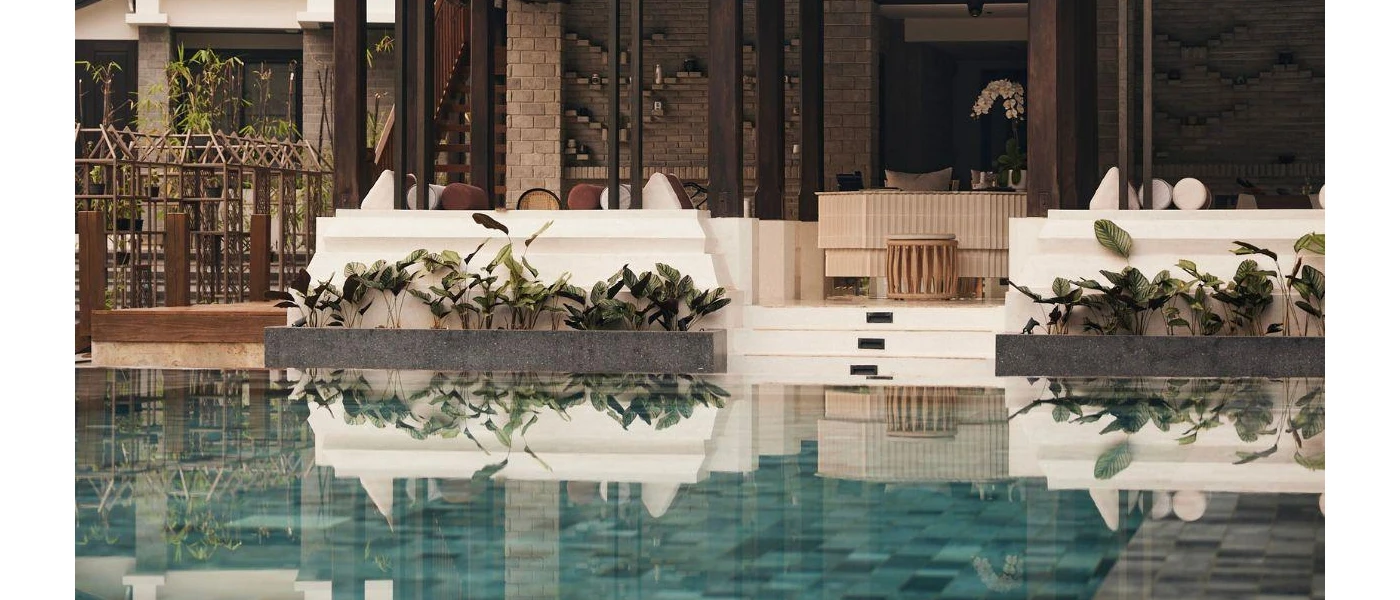 Al fresco terrace with dark-wood columns and stone walls, next to a poolside