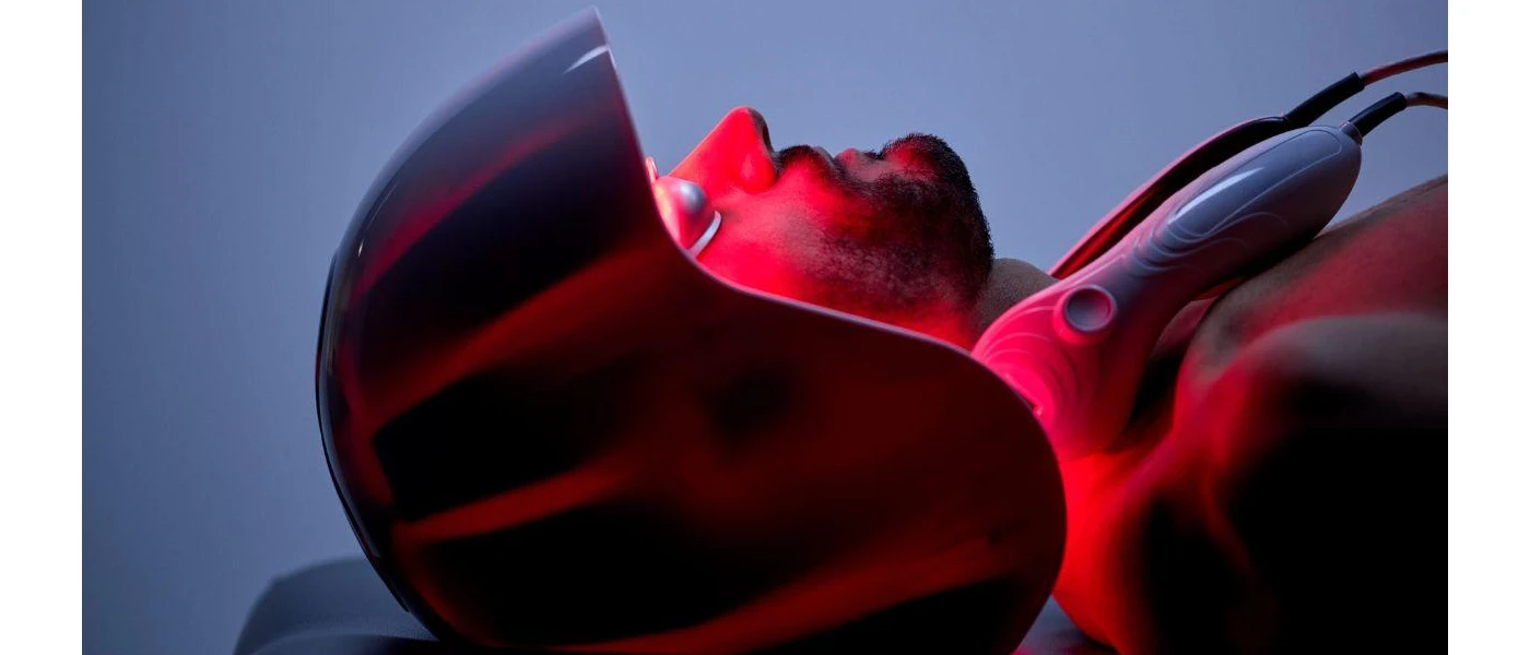 Man lies in a red light contraption in a treatment room