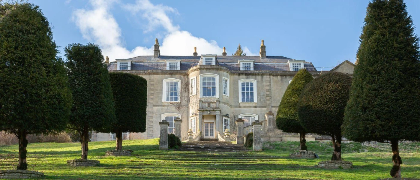Manor-house overlooking a manicured lawn and thick trees