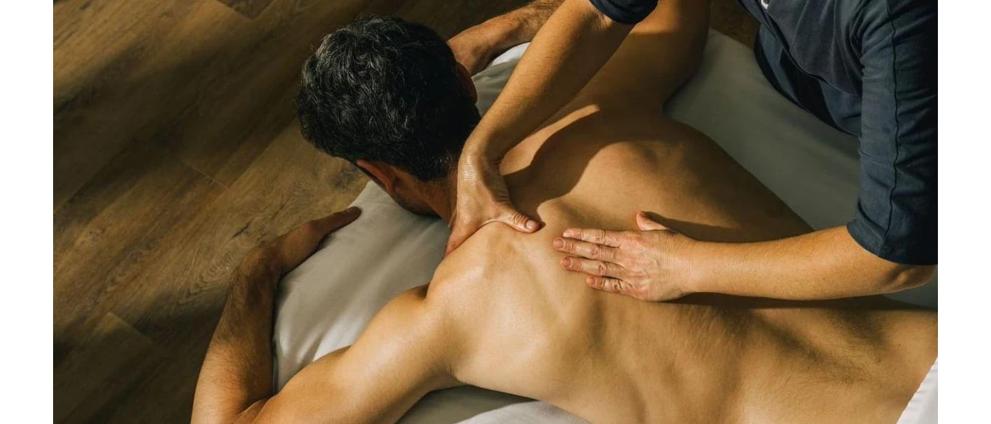 Man lies on his front as a massage therapist works on his back